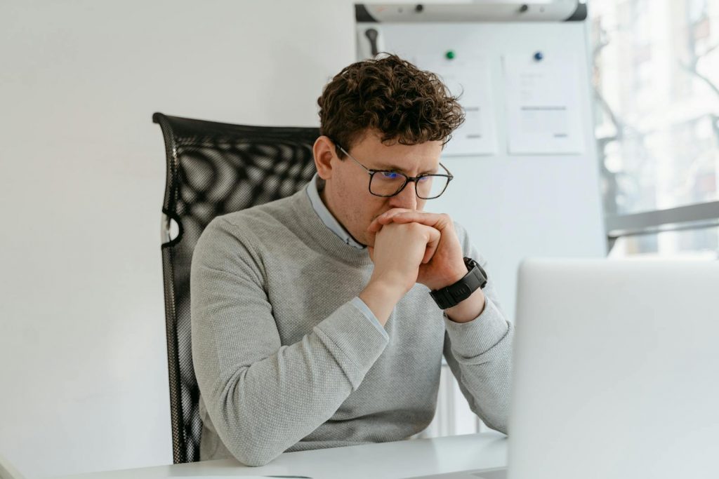 A Man in Gray Sweater Staring at His Laptop